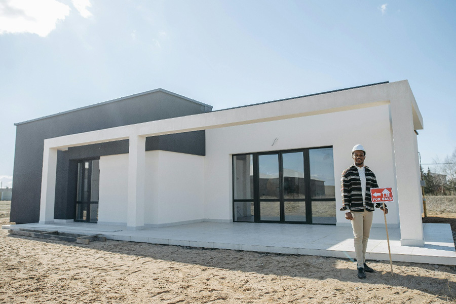 Realtor standing next to a “for sale” sign